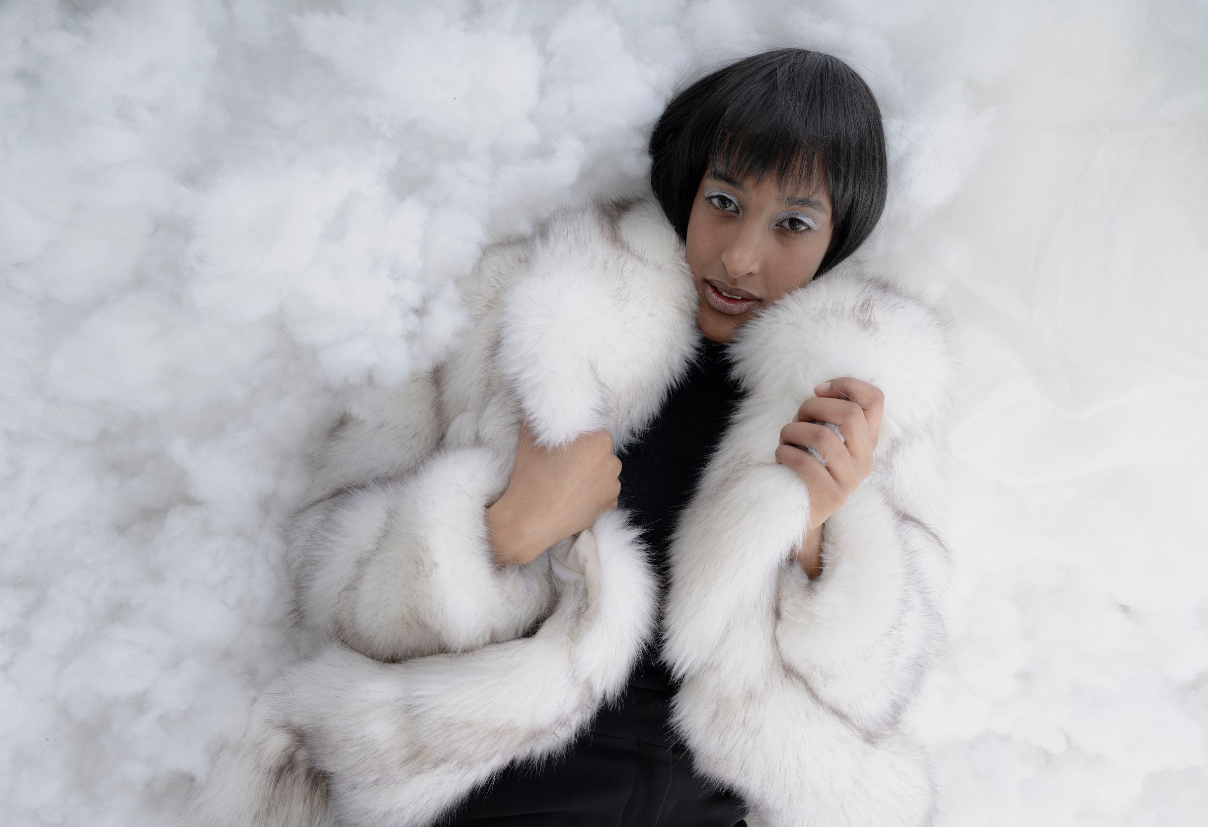 Model in weißem Pelz liegend zwischen Watte, Fashion-Editorial von Serena Scionti