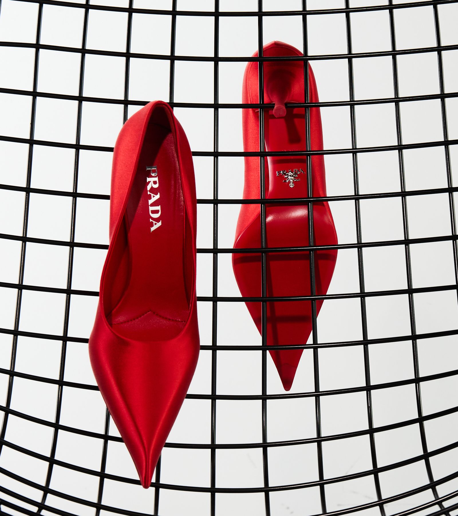 Rote Satin-Pumps von Prada auf einem schwarzen Drahtgitter, von oben fotografiert