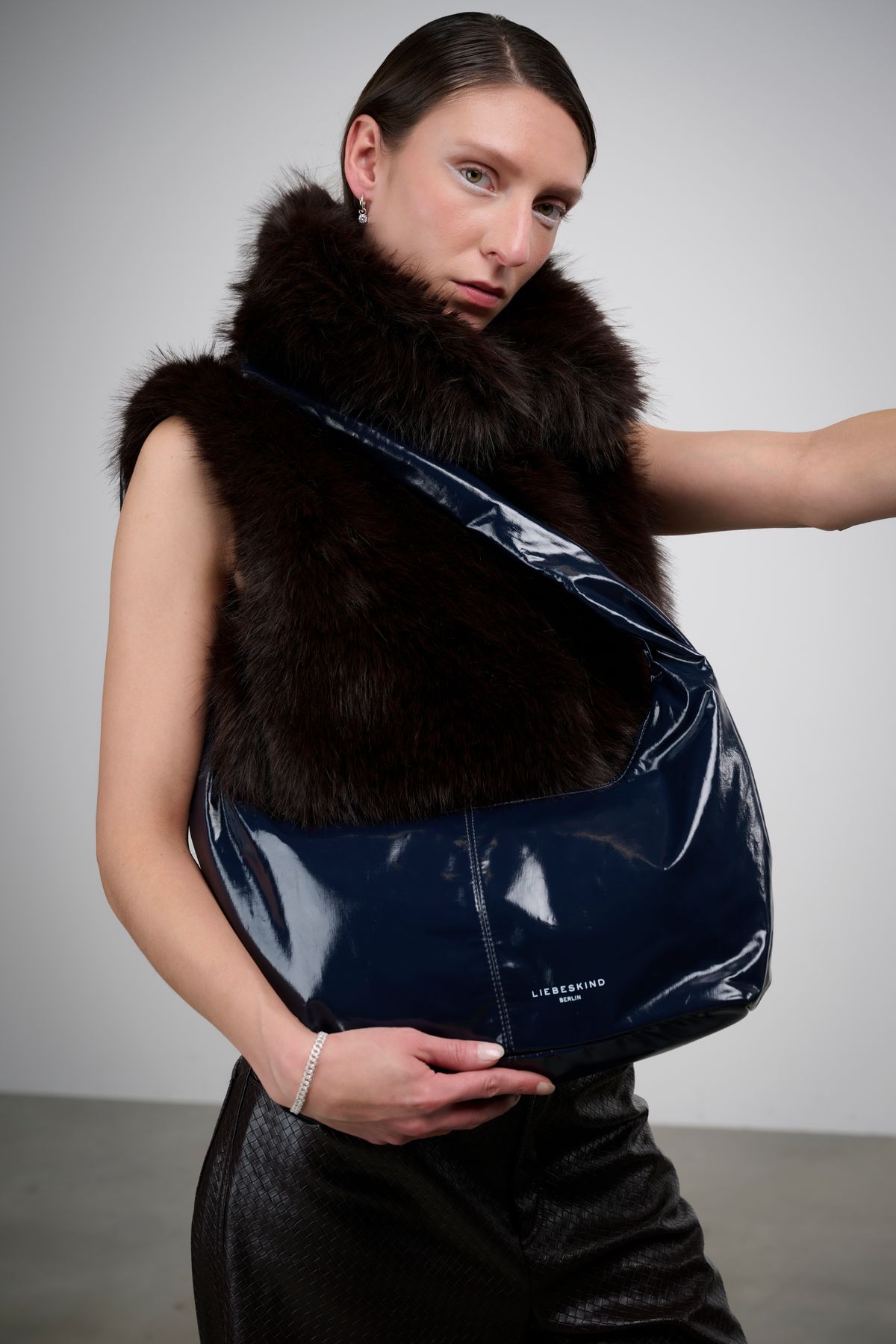 Model mit Pelzweste und dunkelblauer Lacktasche